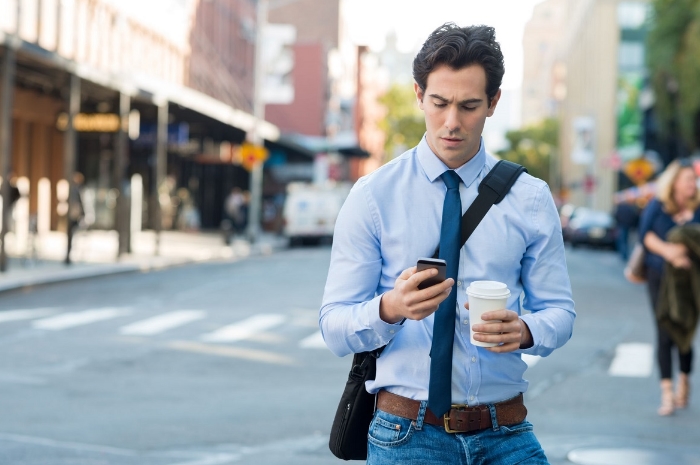 Homem andando na rua e mexendo no celular