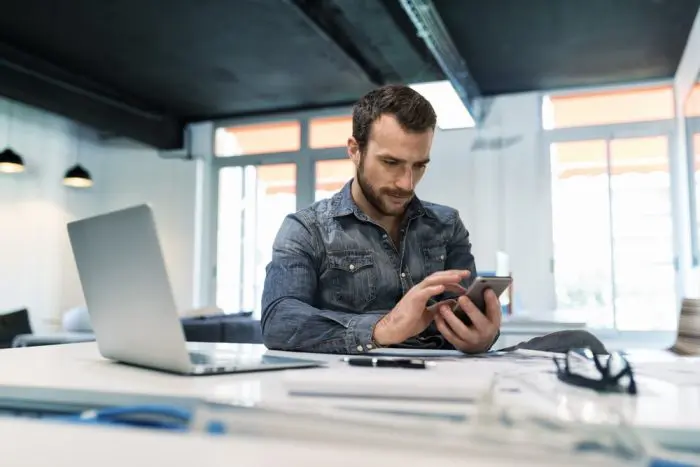 uso das redes sociais no trabalho homem com celular na mão