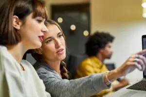 duas mulheres conversando olhando para o computador