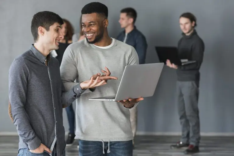 dois homens interagindo com um laptop na mão