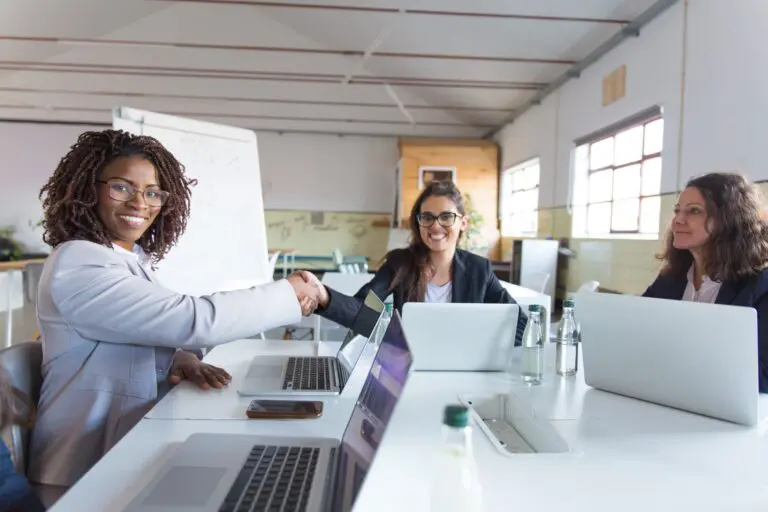 Empresárias apertando as mãos e sorrindo